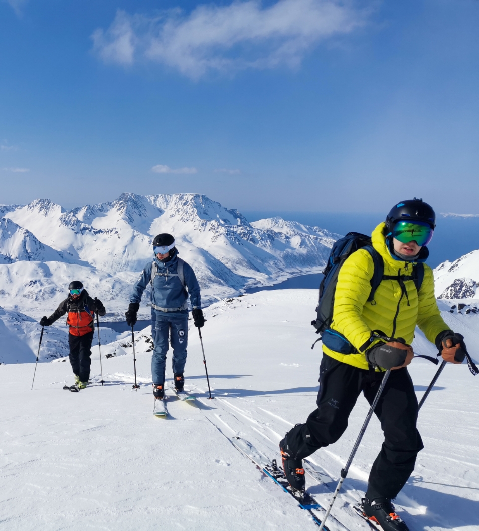 Tre mennesker på skitur i snødekt fjell. Foto.