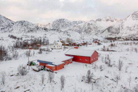 Oversiktsbilde av rødt hus i vinterlandskap. Foto.