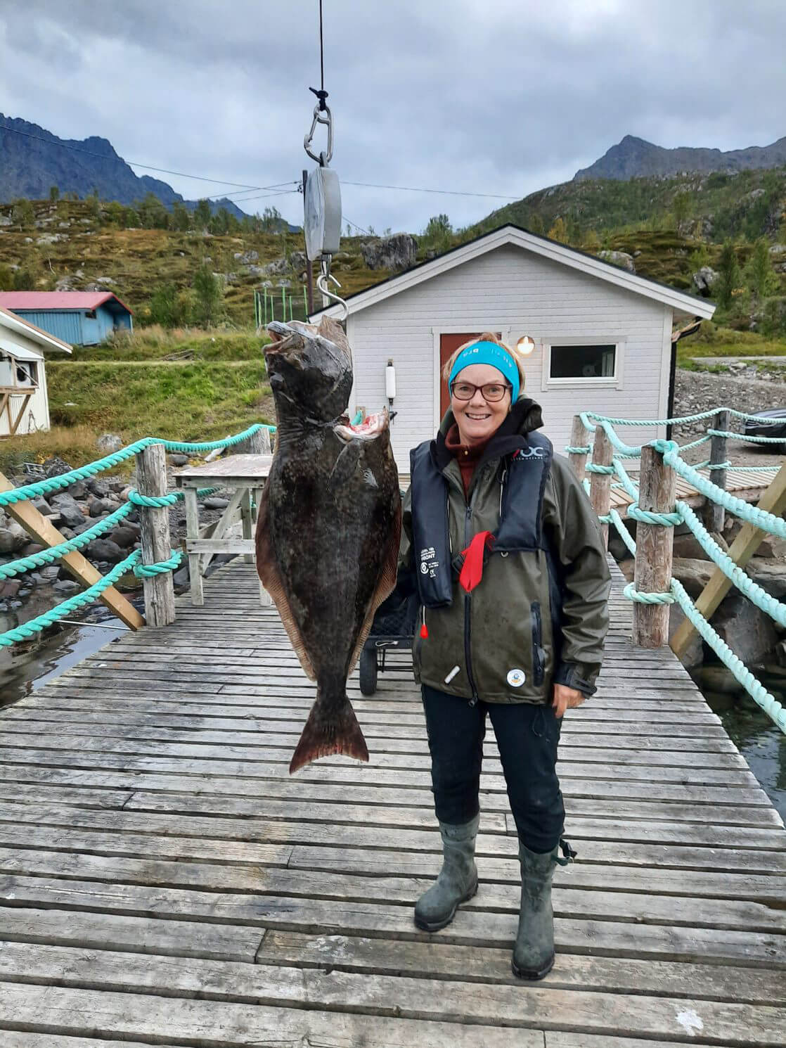 Marianne står ved siden av stor fisk og smiler til kamera.