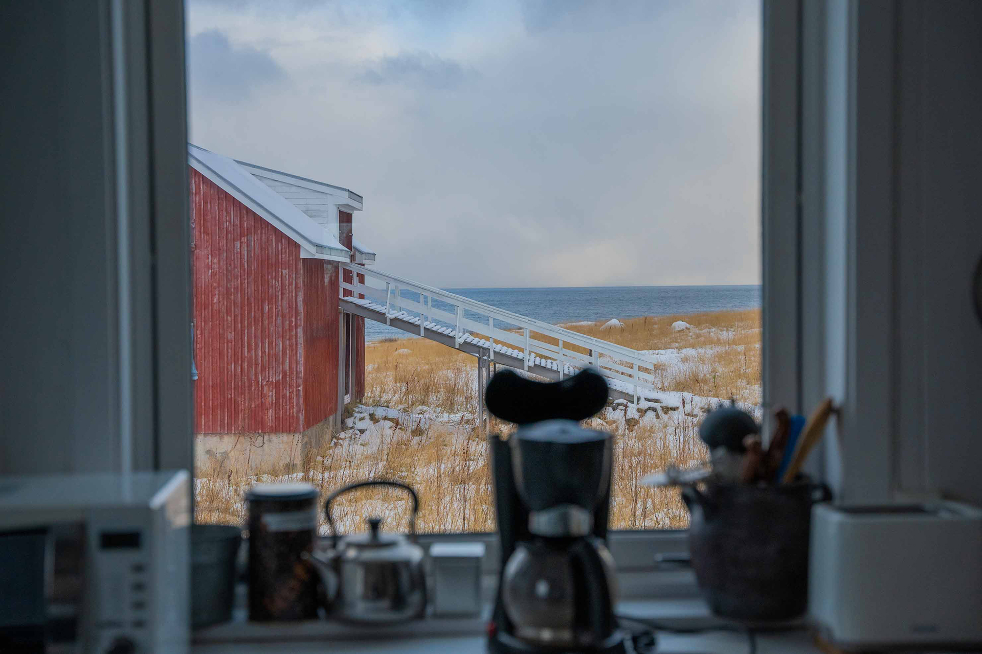 Utsikt ut mot hav og rød låve. Foto.