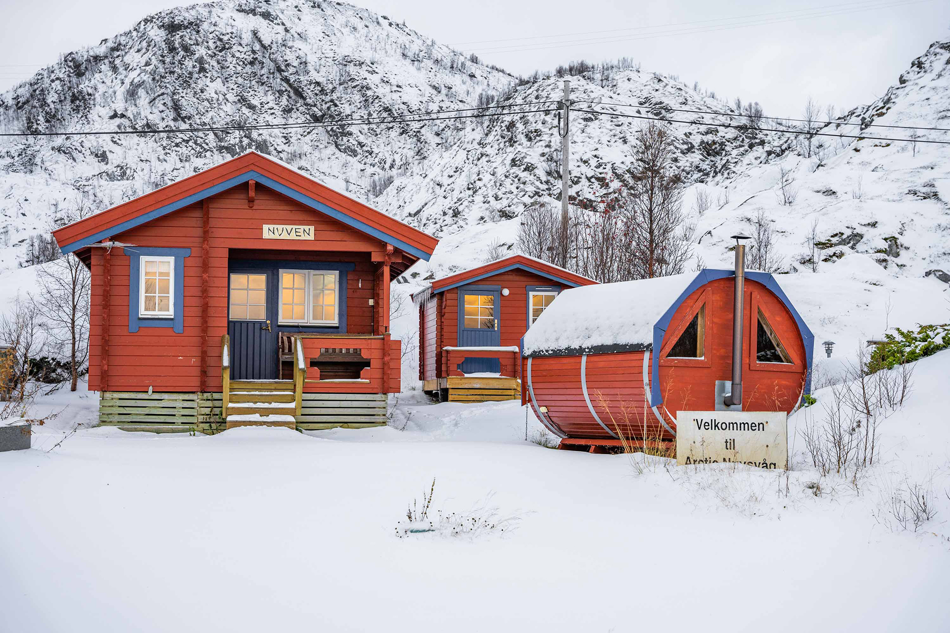 Rød hytte, anneks og badstue i vinterlandskap. Foto.