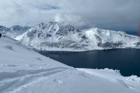 Snødekte fjell og en innsjø fra randonee topptur på ski