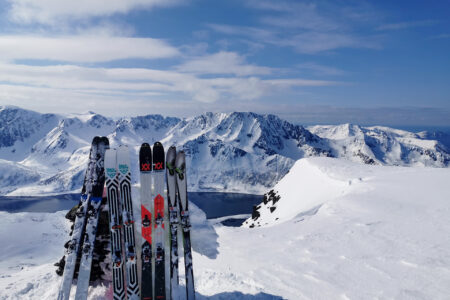 Oppstilte ski stående på snølagt bakke fra randonee topptur i fjellheimen.