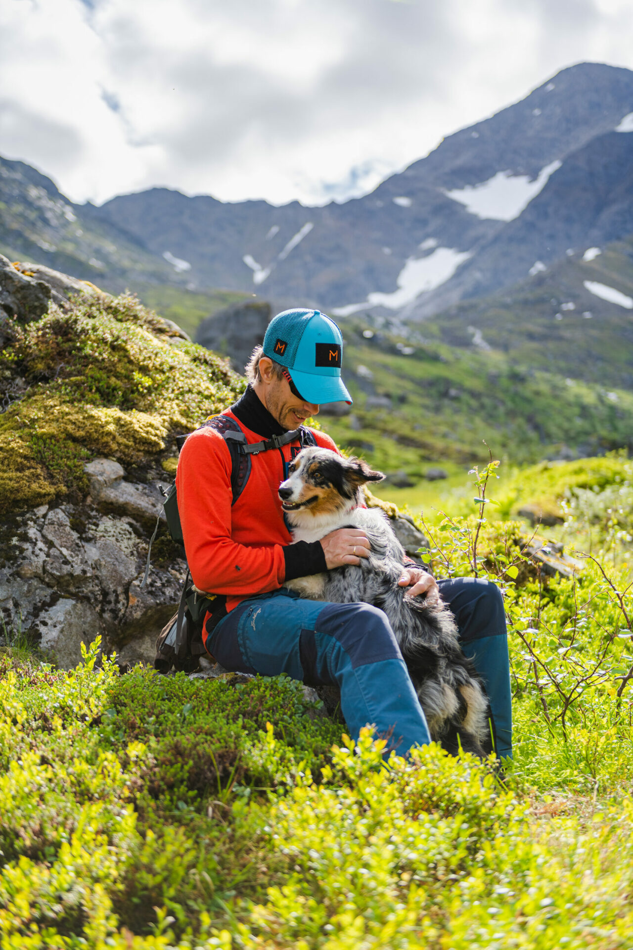 Foto av Stian som sitter sammen med hund i fjellheimen.